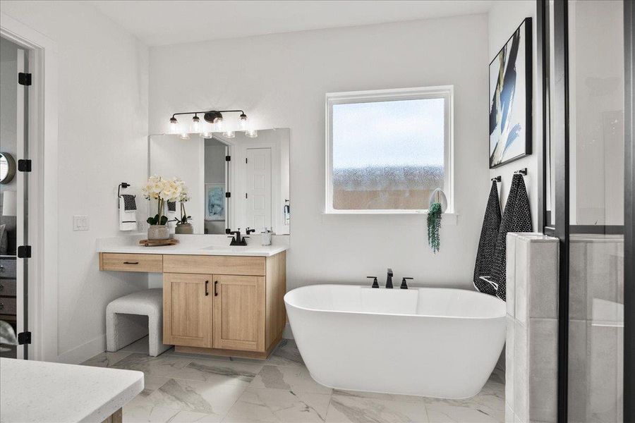 Full bath featuring vanity, a soaking tub, and light marble finish flooring Full bath featuring vanity, a soaking tub, and light marble finish flooring