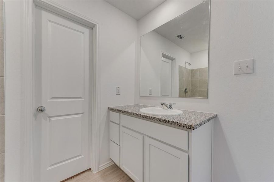 Bathroom with hardwood / wood-style floors, vanity, and a shower