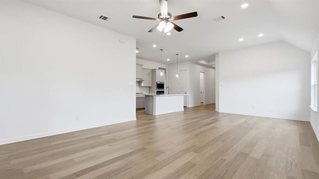Open-concept living area featuring wood-finish flooring, a ceiling fan with integrated lighting, and recessed lighting Open-concept living area featuring wood-finish flooring, a ceiling fan with integrated lighting, and recessed lighting