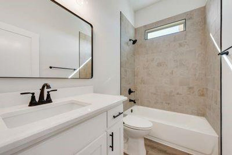 Full bathroom featuring vanity, toilet, tiled shower / bath combo, and hardwood / wood-style floors