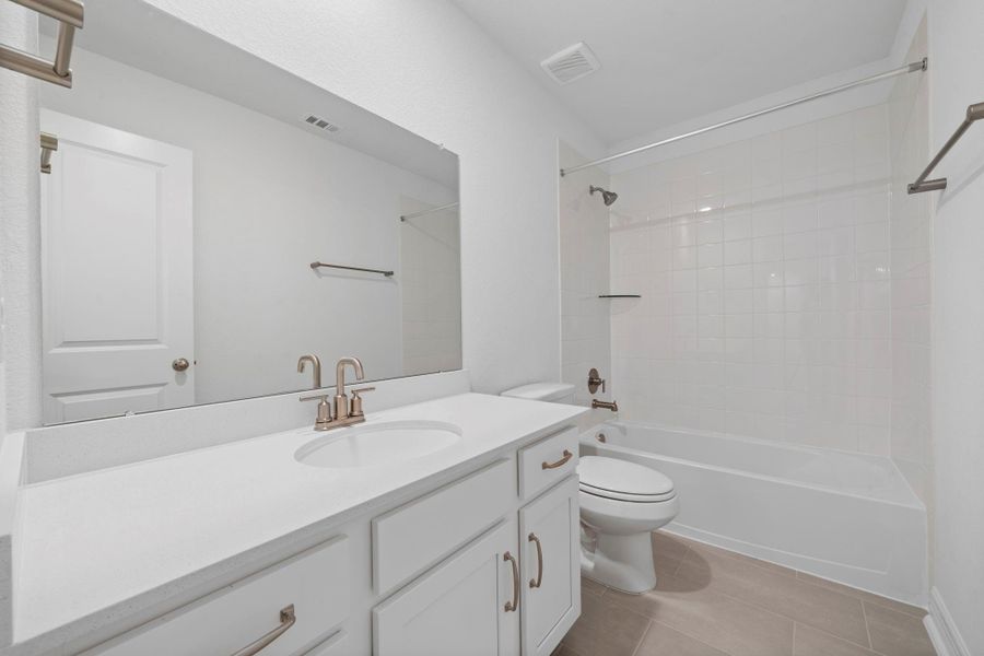 The secondary bath features tile flooring, white cabinetry and light countertops and a shower/tub combo. Perfect for accommodating any visiting family and friends.