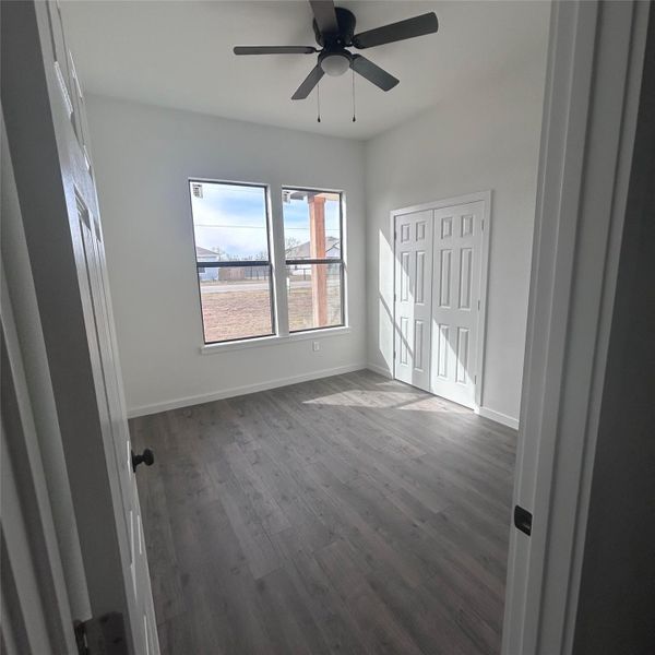 Unfurnished bedroom with dark wood-style flooring and ceiling fan Unfurnished bedroom with dark wood-style flooring and ceiling fan