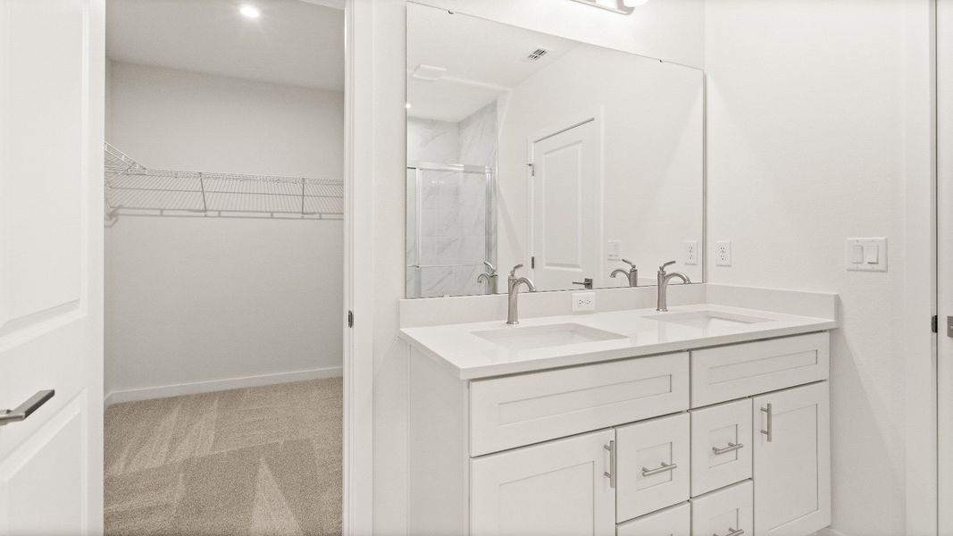 Primary bathroom with double-sink vanity and direct access to walk-in closet in the Castaway model by DRB Homes
