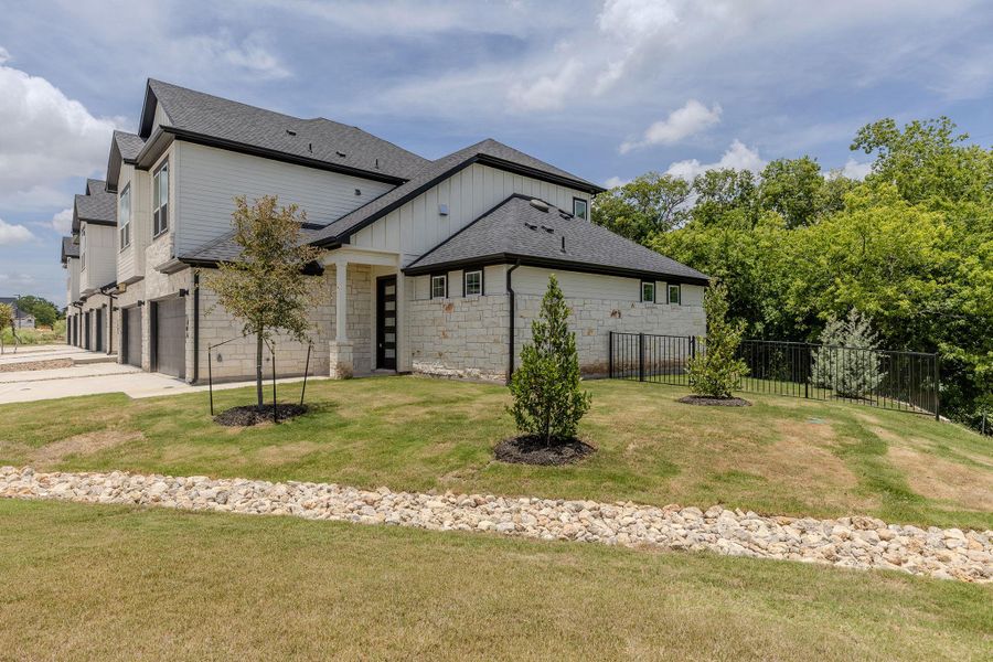 A contemporary townhome with clean lines and a stone facade, offering private garages and a landscaped yard. A contemporary townhome with clean lines and a stone facade, offering private garages and a landscaped yard.