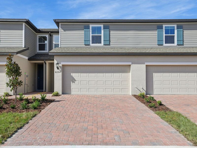 Front exterior of a new home in The Meadow at Crossprairie Townes, St. Cloud, FL, highlighting curb appeal (Image 1). Front exterior of a new home in The Meadow at Crossprairie Townes, St. Cloud, FL, highlighting curb appeal (Image 1).