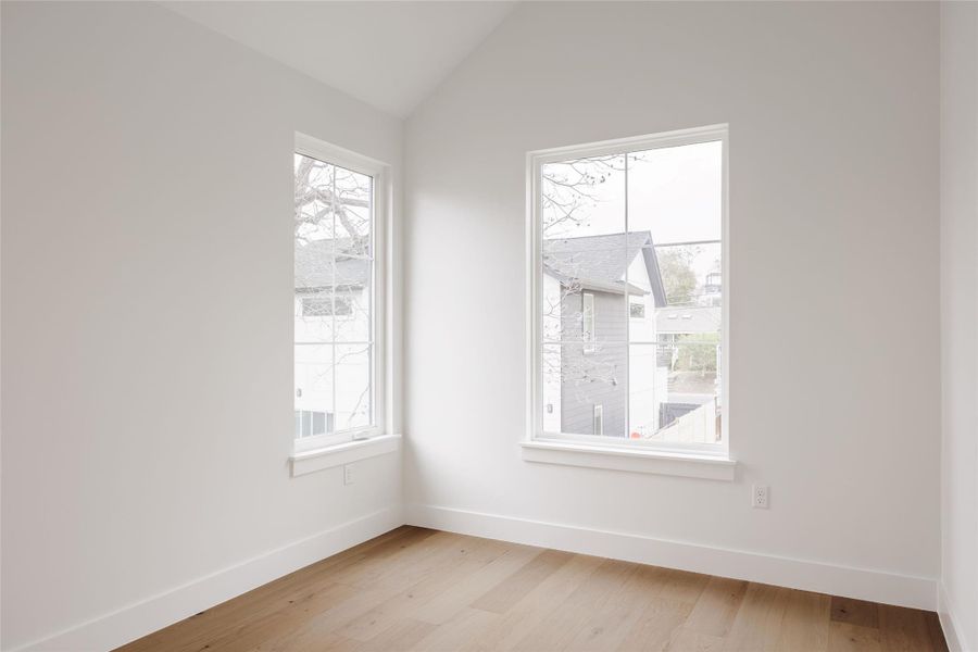 Spare room featuring light wood-style floors and lofted ceiling