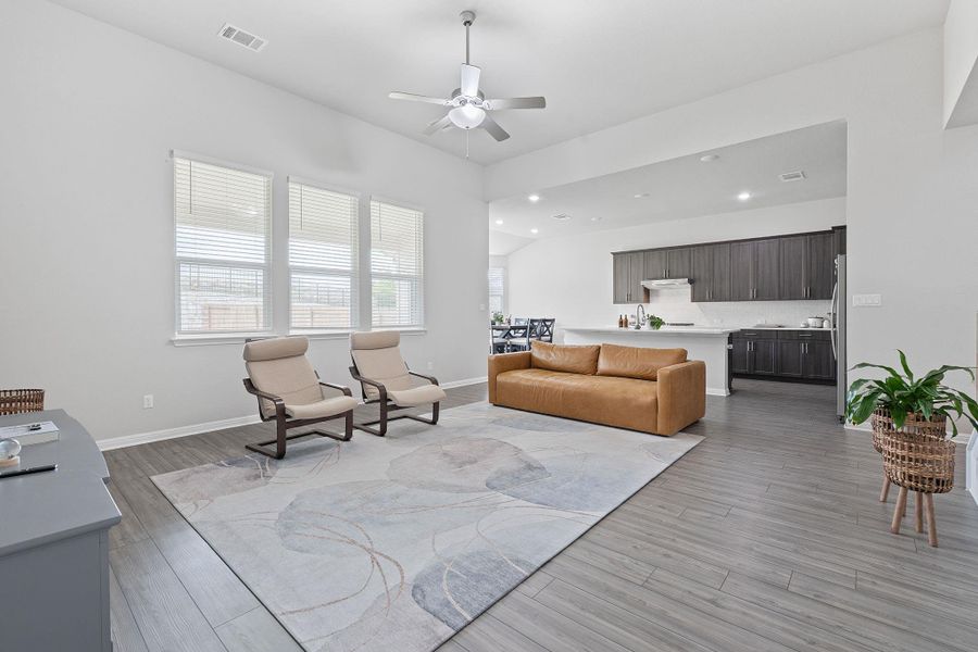 Living room featuring light wood finished floors, baseboards, visible vents, recessed lighting, and a ceiling fan Living room featuring light wood finished floors, baseboards, visible vents, recessed lighting, and a ceiling fan