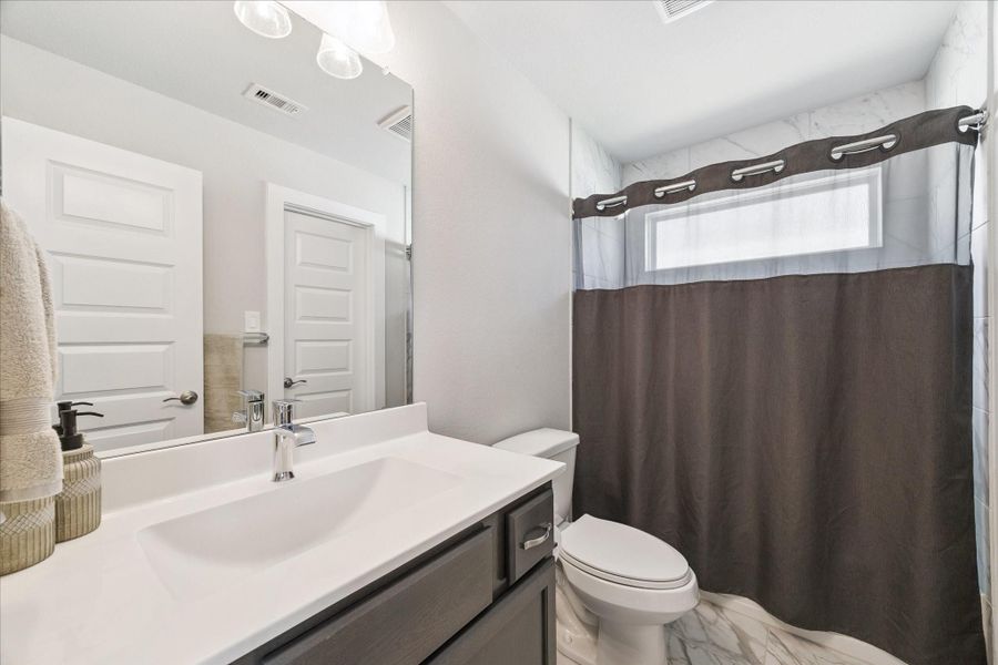 Contemporary bathroom with a white sink, dark cabinetry, and a large mirror. Contemporary bathroom with a white sink, dark cabinetry, and a large mirror.