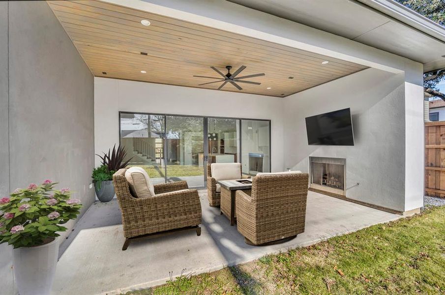 View of patio with an outdoor living space with a fireplace and ceiling fan