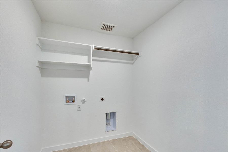 Laundry area featuring hookup for a gas dryer, light tile patterned floors, hookup for a washing machine, and hookup for an electric dryer Laundry area featuring hookup for a gas dryer, light tile patterned floors, hookup for a washing machine, and hookup for an electric dryer