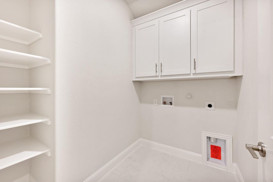 Laundry room with white upper cabinets, open shelving, and washer and dryer hookups on white tile floor
