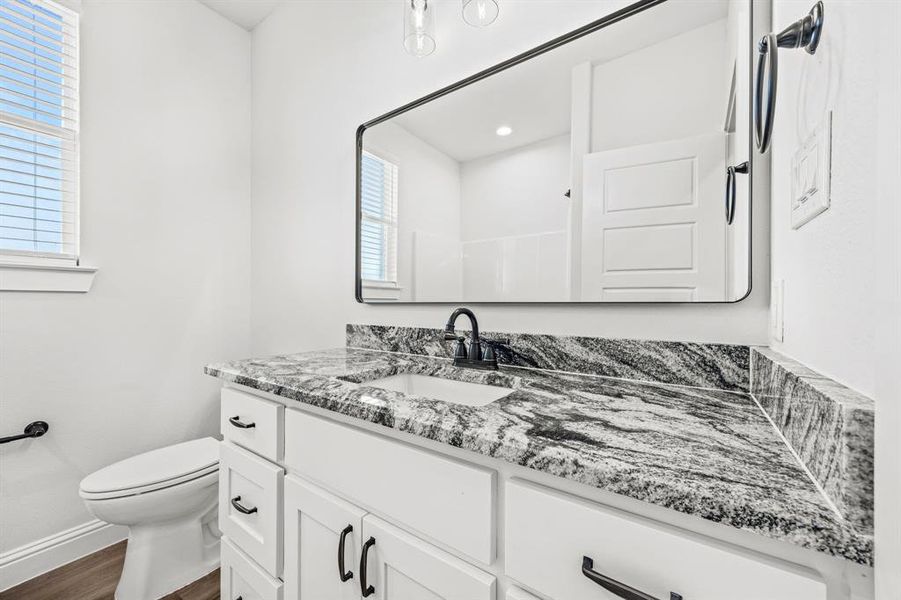 Bathroom with a wealth of natural light, vanity, toilet, and hardwood / wood-style flooring