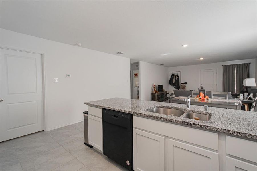 Kitchen with white cabinets, dishwasher, light stone countertops, light tile patterned floors, and recessed lighting