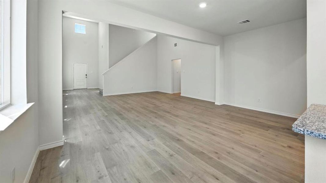 Unfurnished living room featuring light wood-type flooring, stairs, and recessed lighting