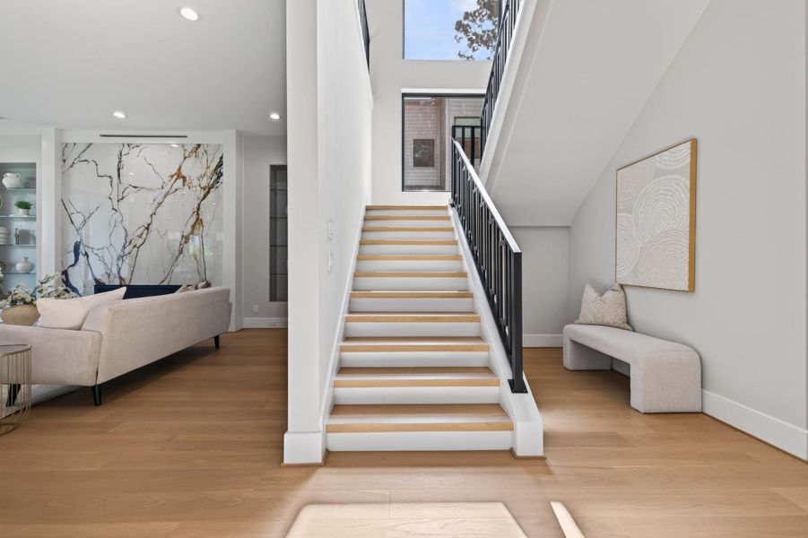 Elegant floating staircase with wood treads and iron railings, flooded with natural light.