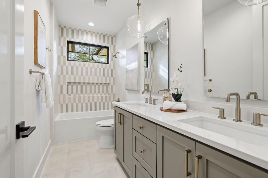 Bathroom featuring shower / bath combination, double vanity, and light tile patterned floors
