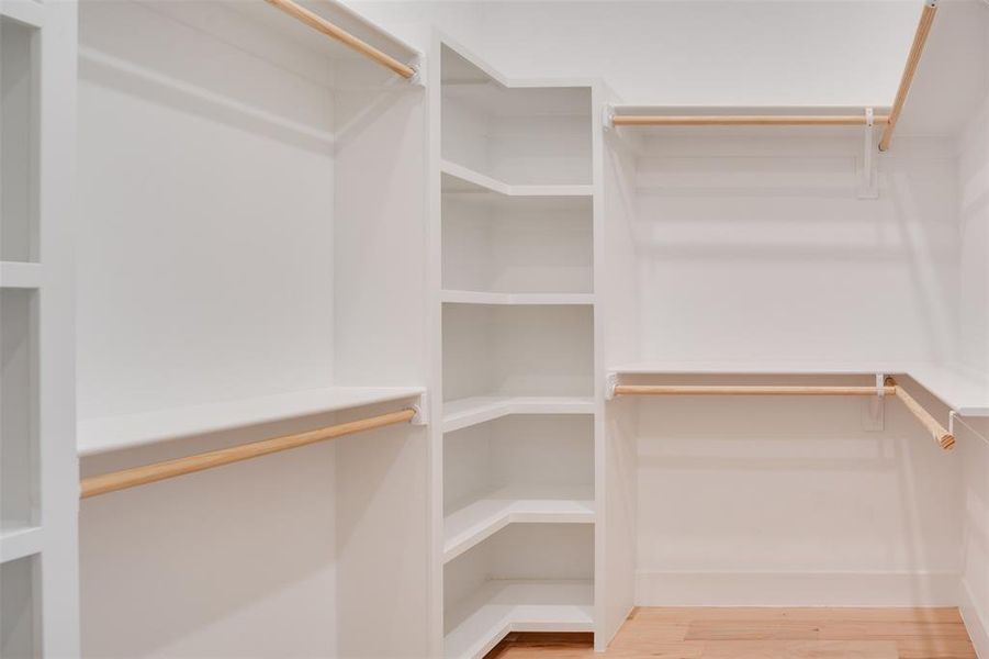 Walk in closet with hardwood / wood-style flooring