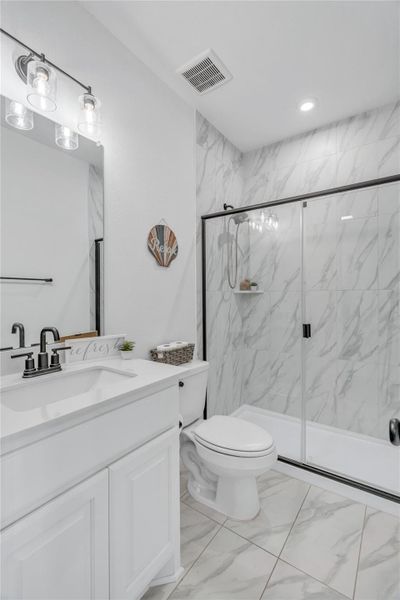 A well-lit bathroom features a spacious shower and a modern vanity with ample counter space.