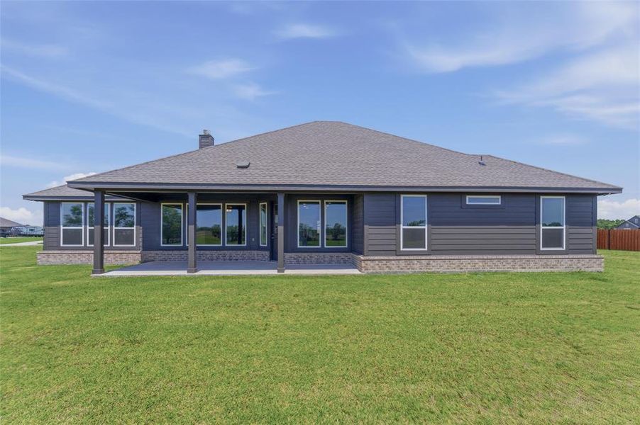 Rear exterior featuring a covered patio, multiple windows, dark gray siding, and a stone-clad foundation Rear exterior featuring a covered patio, multiple windows, dark gray siding, and a stone-clad foundation