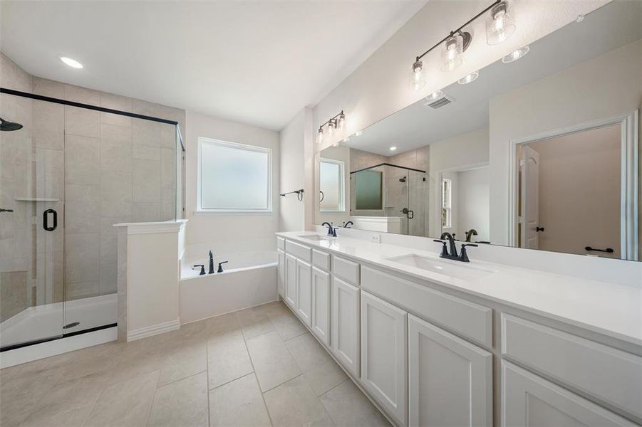 Bathroom with double vanity, a stall shower, a garden tub, and tile patterned flooring