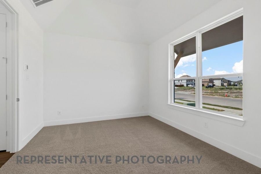 The primary bedroom is brightened by windows that invite natural light, creating a serene space to relax and unwind.