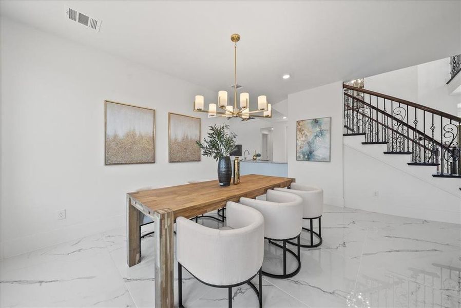 Dining area with stairs, a chandelier, light marble finish floors, and recessed lighting Dining area with stairs, a chandelier, light marble finish floors, and recessed lighting
