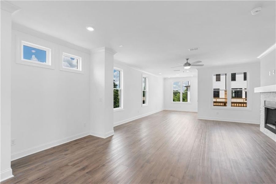 Unfurnished living room featuring ornamental molding, a fireplace, dark wood-type flooring, recessed lighting, and a ceiling fan Unfurnished living room featuring ornamental molding, a fireplace, dark wood-type flooring, recessed lighting, and a ceiling fan