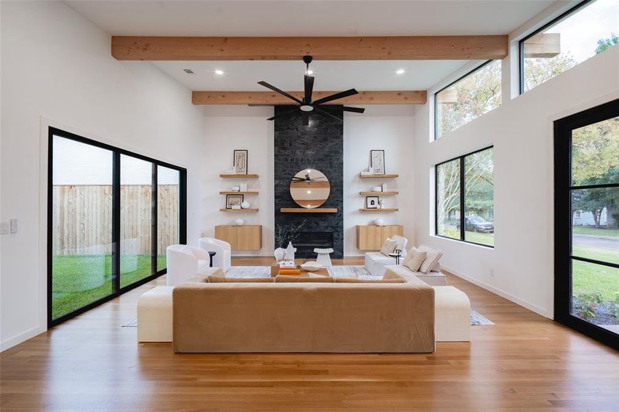 Living room featuring light hardwood / wood-style flooring, a fireplace, beam ceiling, and a healthy amount of sunlight