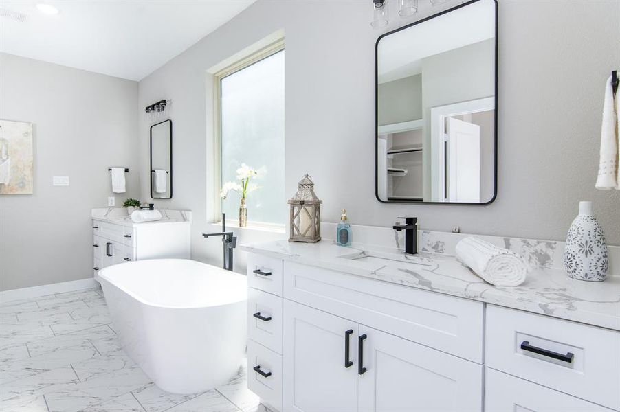 Primary bath with elegant calacatta quartz, free standing soaking tub, and separate vanities.