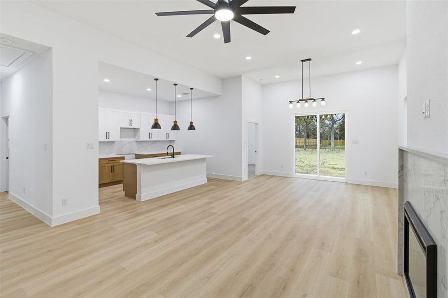 Unfurnished living room featuring light wood finished floors, a ceiling fan, recessed lighting, and attic access