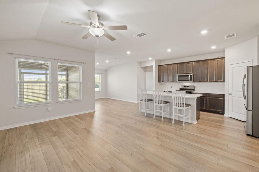 Kitchen with a kitchen island with sink, a kitchen bar, open floor plan, appliances with stainless steel finishes, and dark brown cabinets Kitchen with a kitchen island with sink, a kitchen bar, open floor plan, appliances with stainless steel finishes, and dark brown cabinets