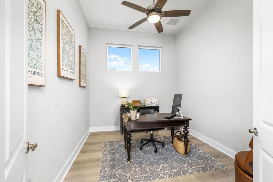 Well-lit private study, featuring warm wood-look flooring, is perfect for working from home.