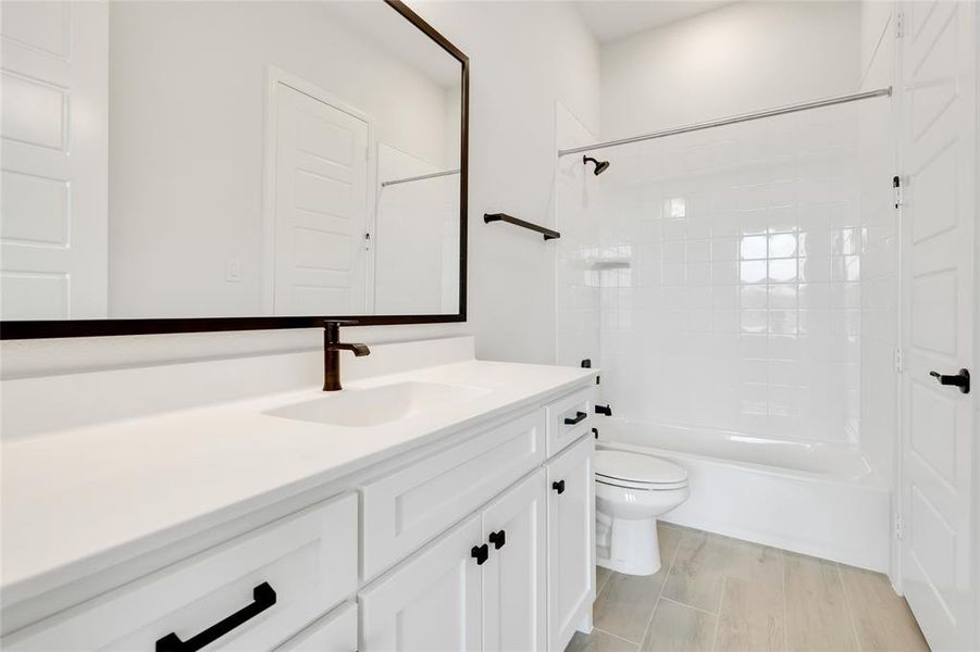 Full bathroom with wood-type flooring, tiled shower / bath, vanity, and toilet