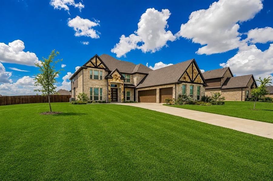 Stone and brick facade with dark timber accents, a multi-gabled roofline, and a three-car garage