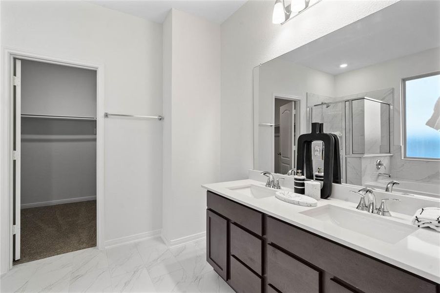 This primary bathroom is definitely move-in ready! Featuring a framed walk-in shower with tile surround, separate garden tub for soaking after a long day with custom tile detailing, dark stained cabinets with light countertops, spacious walk-in closet with shelving, high ceilings, custom paint, sleek and modern finishes.