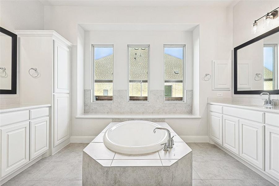 Bathroom featuring tile patterned flooring, a relaxing tiled tub, and vanity