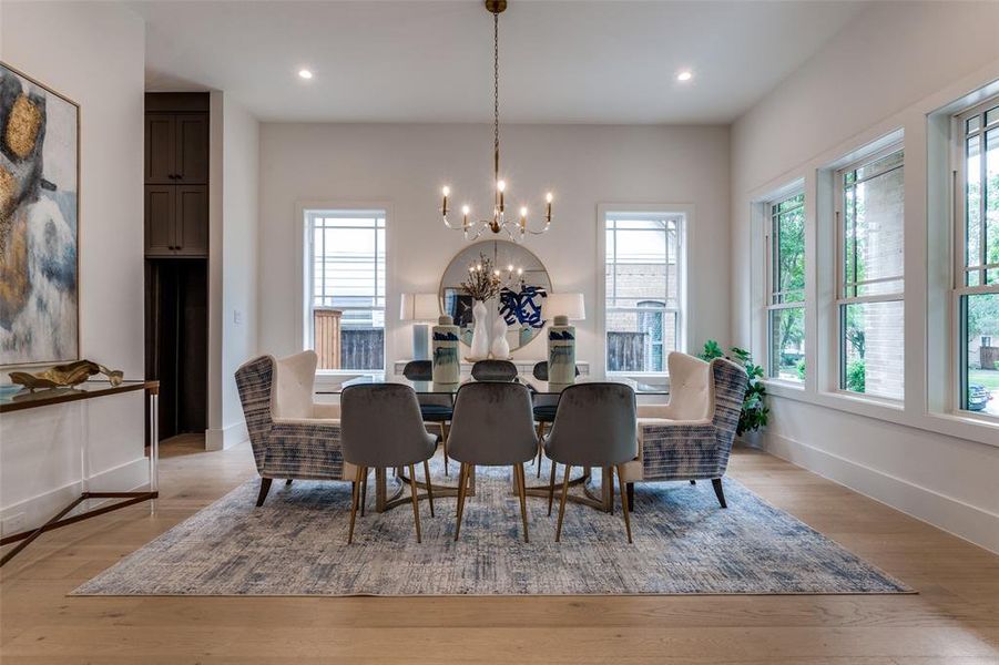 Dining room featuring baseboards, light wood finished floors, an inviting chandelier, and recessed lighting Dining room featuring baseboards, light wood finished floors, an inviting chandelier, and recessed lighting