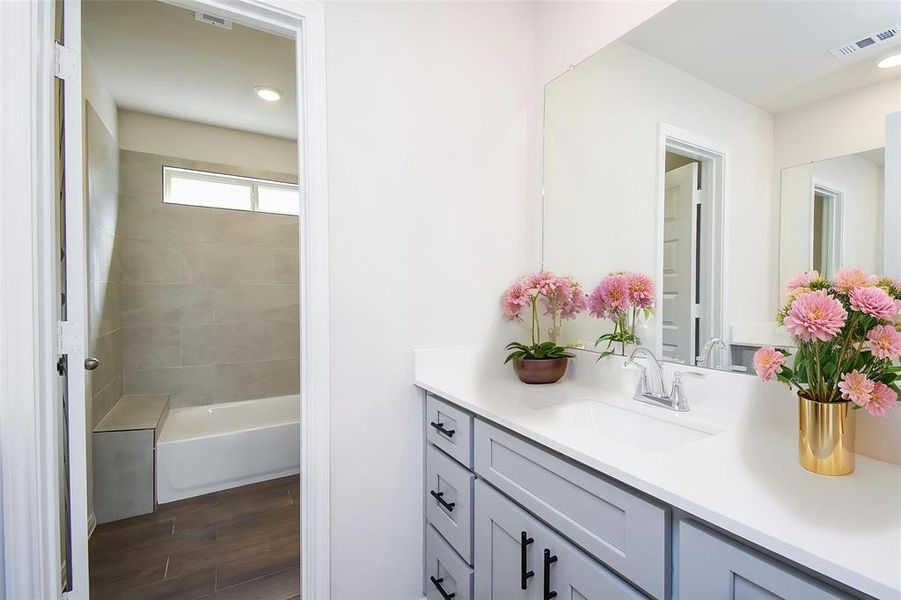 The well-lit bathroom features a modern vanity with sleek gray cabinetry and a spacious countertop. The well-lit bathroom features a modern vanity with sleek gray cabinetry and a spacious countertop.