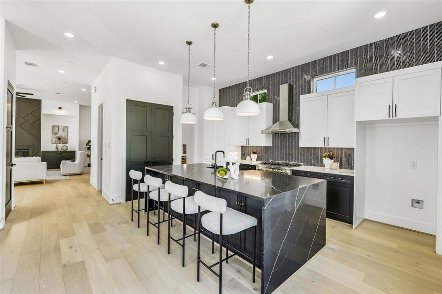 This open-concept chef’s kitchen blends elegance and efficiency, ideal for busy professionals who love to entertain. The bold waterfall-edge quartz island, 6-burner ZLINE gas range, and full-height herringbone backsplash are complemented by soft-close custom cabinetry and brass-accented hardware. Expansive sightlines flow effortlessly into the living area, creating a sense of calm and connected luxury—perfect after long days in the Texas Medical Center. This open-concept chef’s kitchen blends elegance and efficiency, ideal for busy professionals who love to entertain. The bold waterfall-edge quartz island, 6-burner ZLINE gas range, and full-height herringbone backsplash are complemented by soft-close custom cabinetry and brass-accented hardware. Expansive sightlines flow effortlessly into the living area, creating a sense of calm and connected luxury—perfect after long days in the Texas Medical Center.