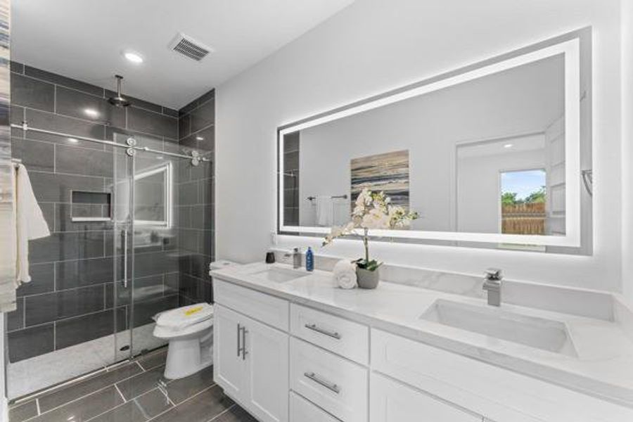 Bathroom with double vanity, a stall shower, recessed lighting, and dark tile patterned flooring Bathroom with double vanity, a stall shower, recessed lighting, and dark tile patterned flooring