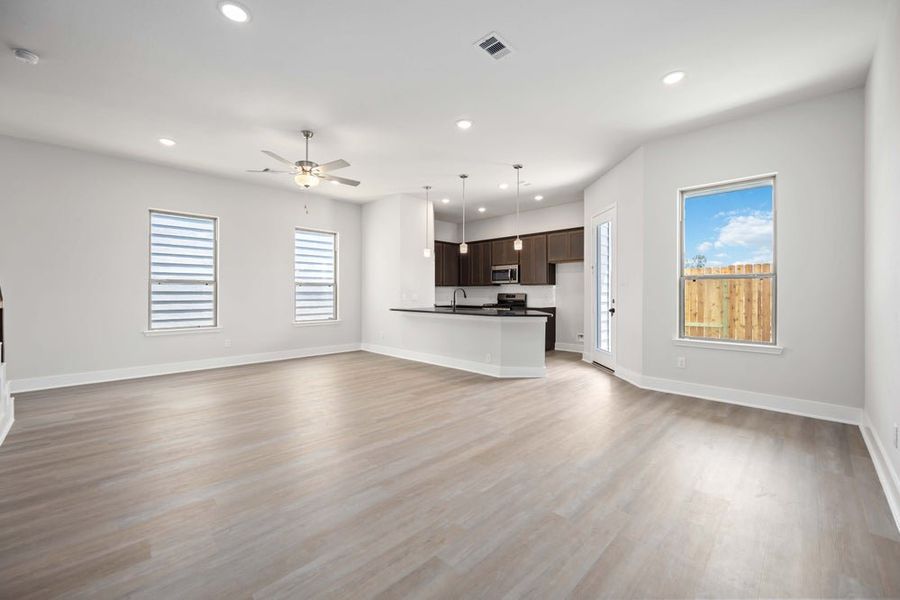 Open-concept living room and kitchen with light wood floors and dark cabinets Open-concept living room and kitchen with light wood floors and dark cabinets