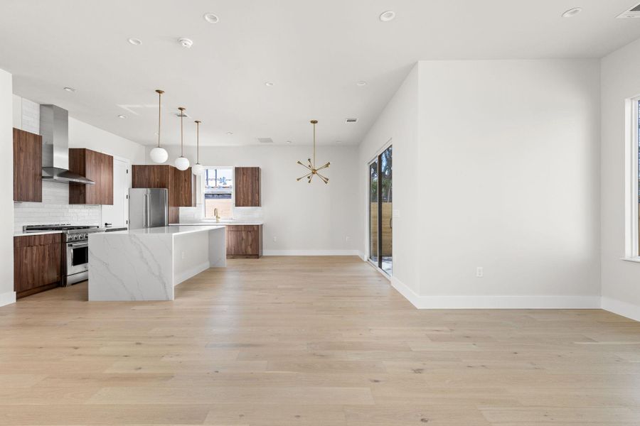 Kitchen with a kitchen island, high quality appliances, decorative backsplash, modern cabinets, and wall chimney exhaust hood