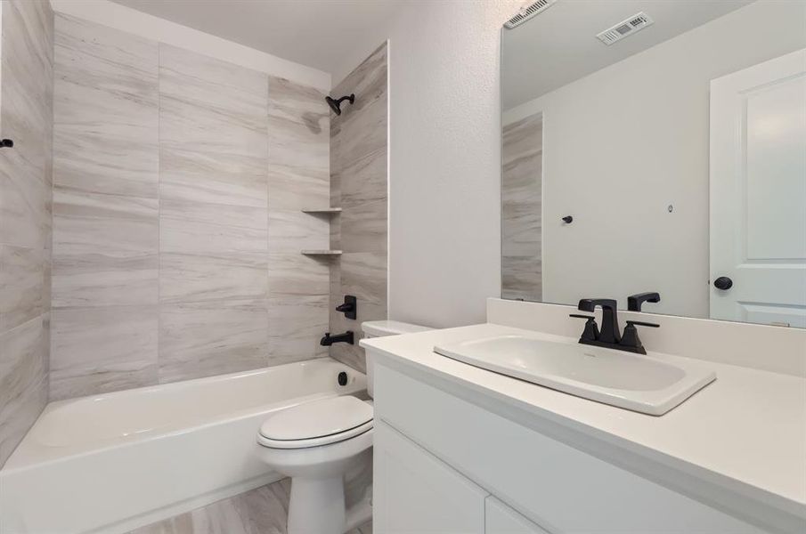 Full bathroom with tiled shower / bath, vanity, and toilet