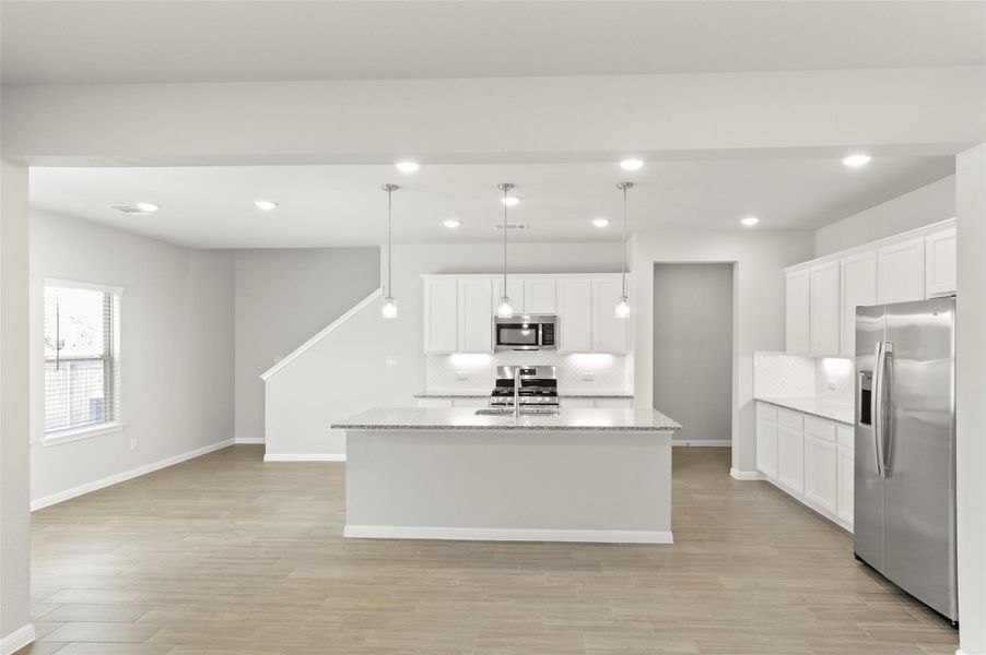 Kitchen with appliances with stainless steel finishes, decorative backsplash, light wood-style flooring, baseboards, and recessed lighting