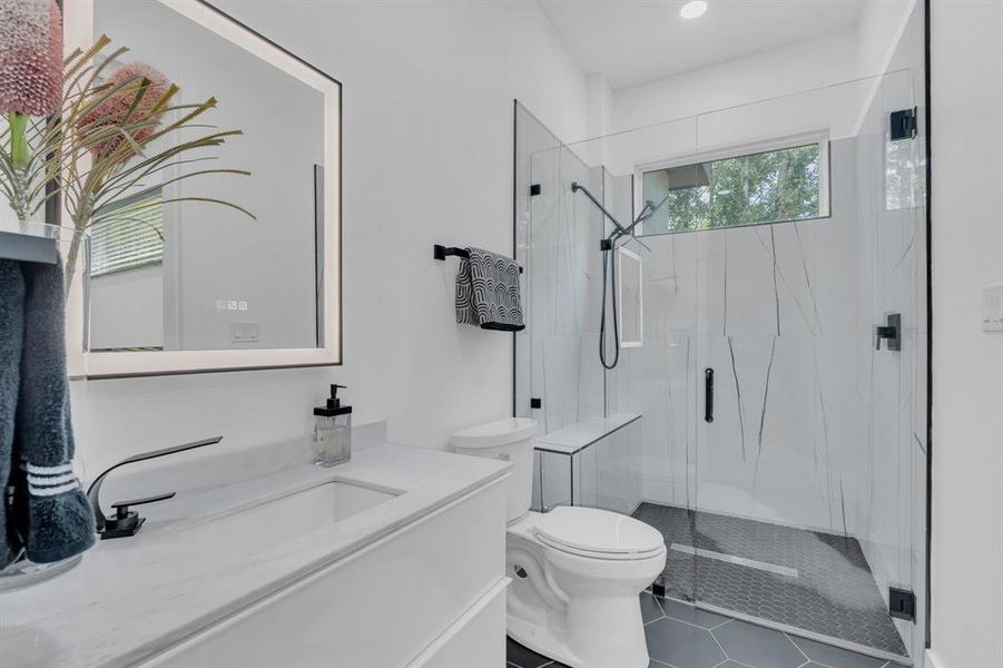 Bathroom with a marble finish shower, vanity, and dark tile patterned flooring