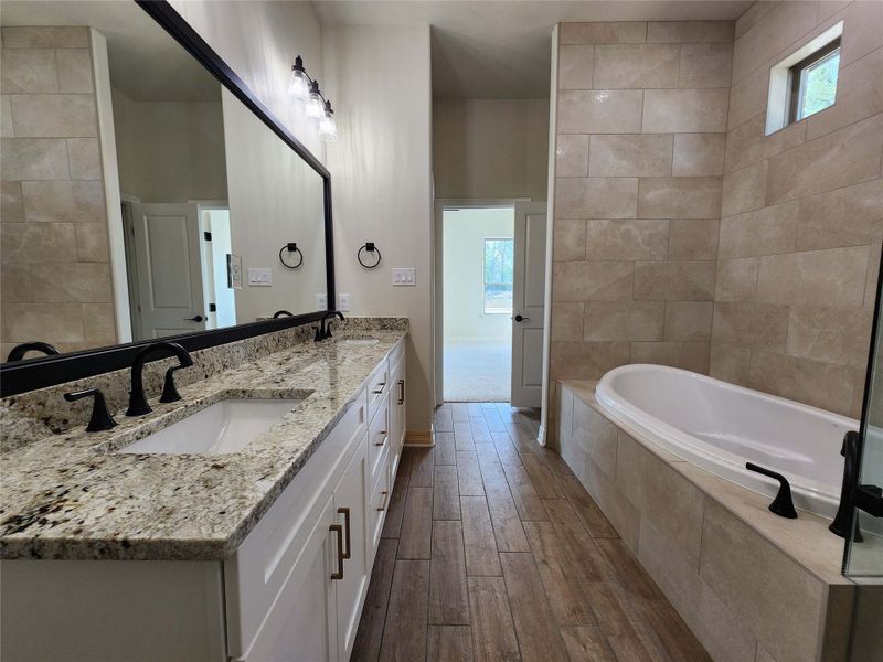 Bathroom with a garden tub, double vanity, and dark wood finished floors