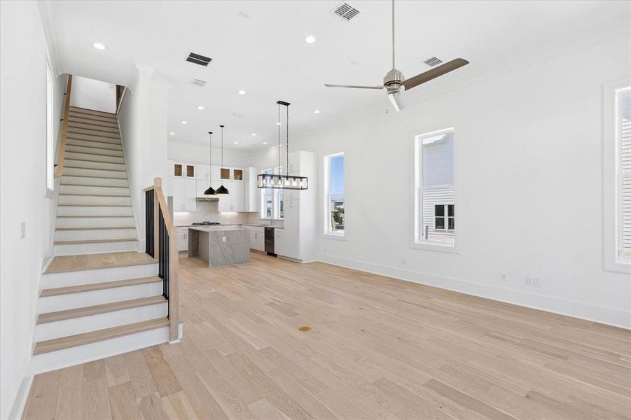 Open-concept living space featuring light wood-finish flooring, white walls, and a contemporary ceiling fan