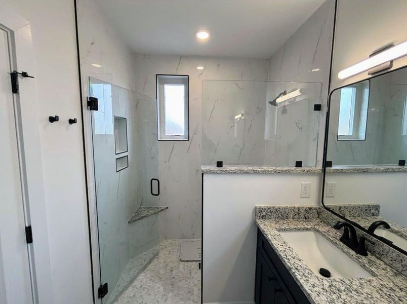 Full bathroom with a marble finish shower and vanity