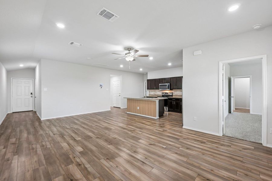 Open-concept living space with wood-finish flooring throughout, recessed lighting, and a ceiling fan