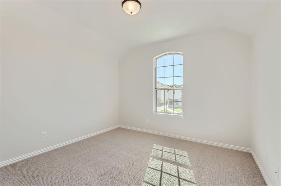 Empty room with vaulted ceiling and carpet